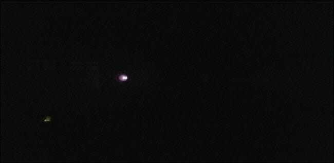 A darkened picture with visible bright lights in the distance.