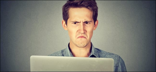 A man frowning at a MacBook screen.