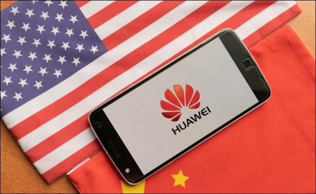 A Huawei phone between a USA and Chinese flag.