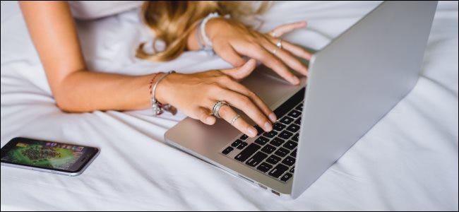 A woman using a MacBook on a bed, which is bad for cooling.
