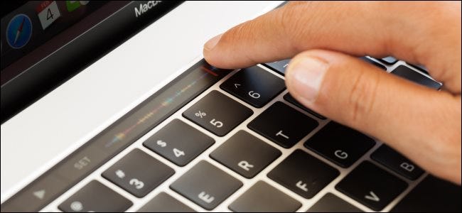 A hand touching the touch bar on a MacBook Pro.