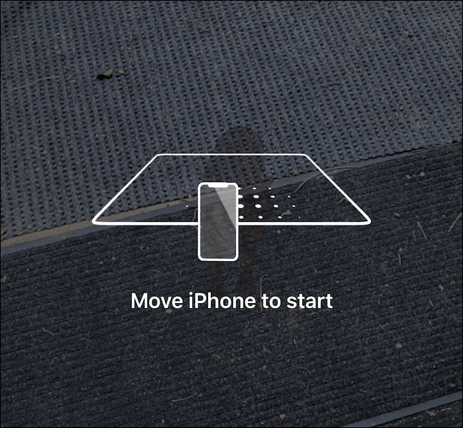 A phone scanning the ground to load the AR experience.