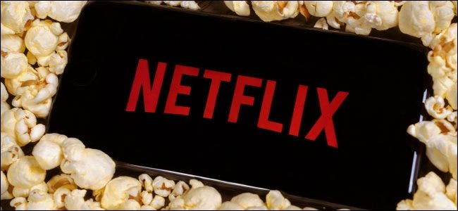 The Netflix logo on a smartphone sitting on a pile of popcorn.