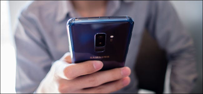 man wearing gray shirt use blue Samsung S9 plus